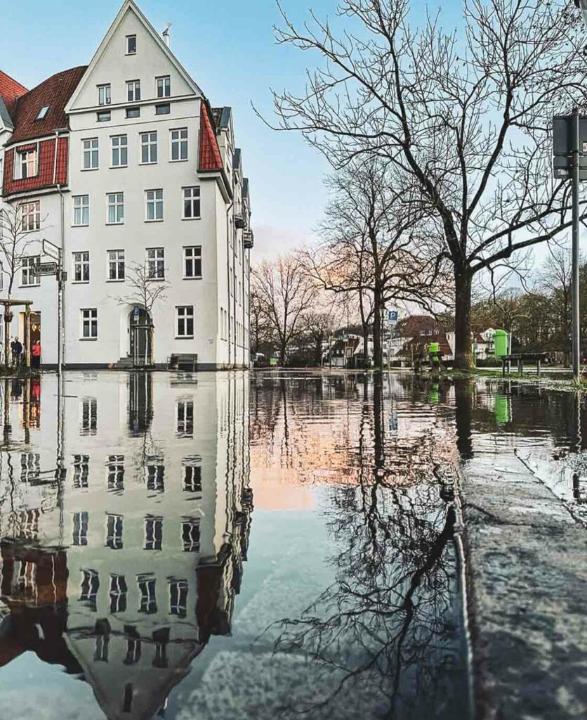 Das ist ein Foto eines traditionellen Gebäudes in Lübeck samt einer Reflexion auf nasser Oberfläche